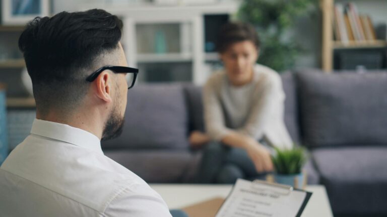 A therapist and patient engaged in a discussion during a session inside an office setting.